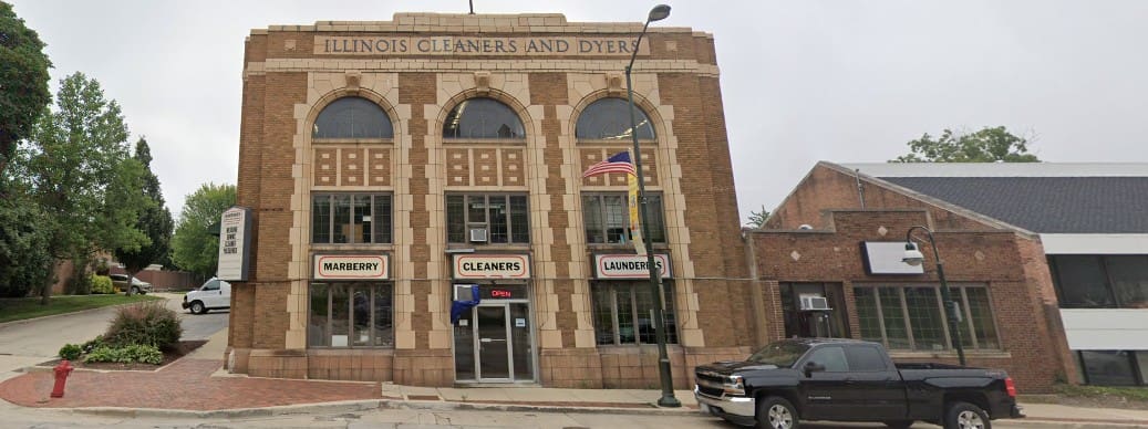Two-story brick building labeled "Illinois Cleaners and Dyers" with large arched windows, American flag, and signage for "Marberry Cleaners" and "Launderers.